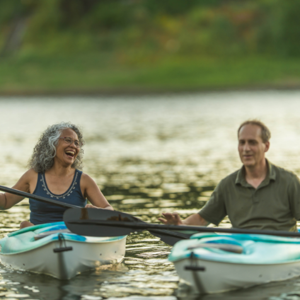 couple paddling in kayaks laughing having fun
